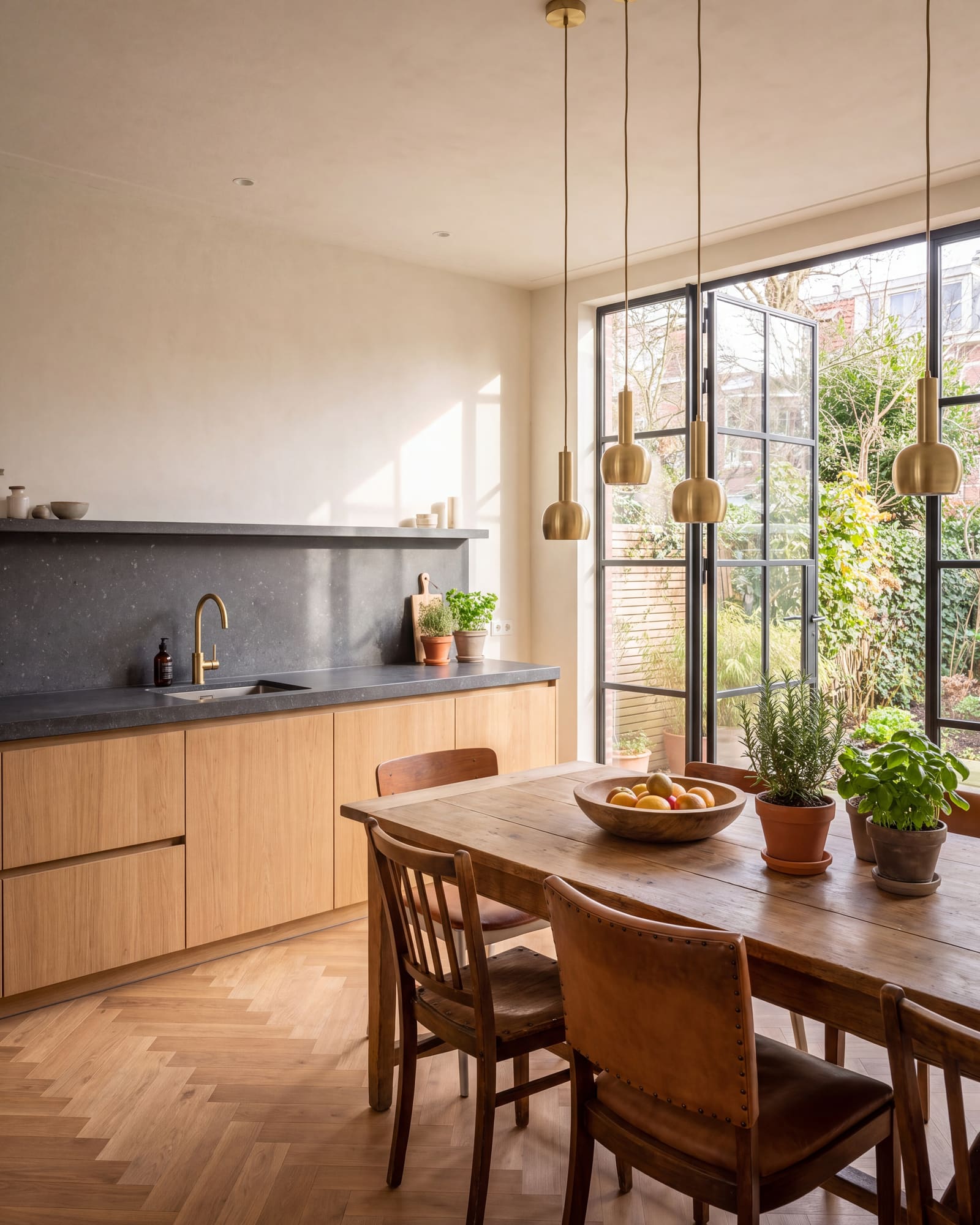 Keuken met eiken kasten, blad van blauwe hardsteen en een stalen pui naar de tuin